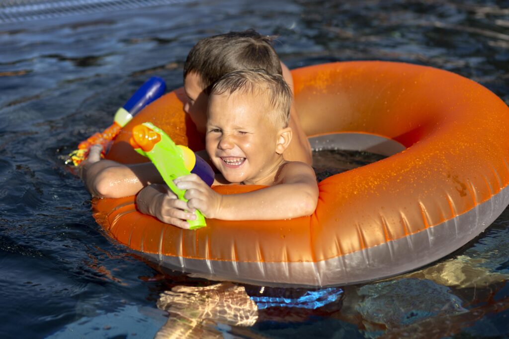 chicos-divirtiendose-piscina-flotador-pistola-agua - Mallorca Global Charter